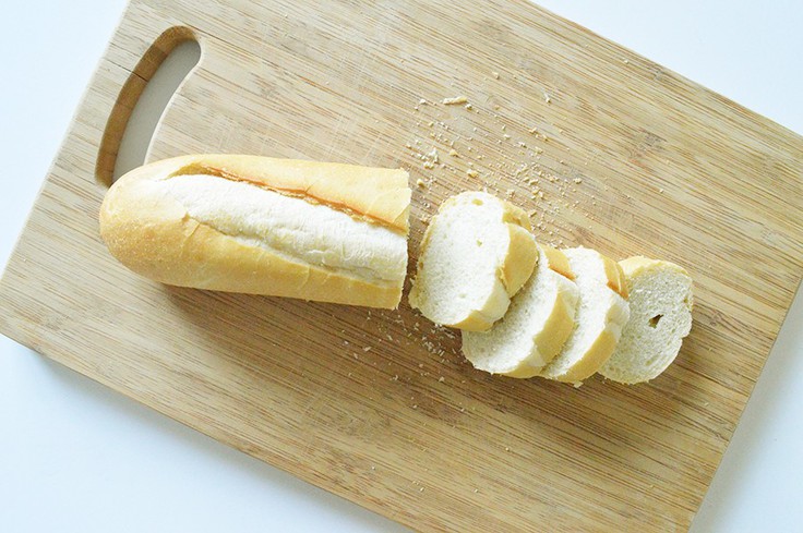A sliced baguette on a wooden cutting board.