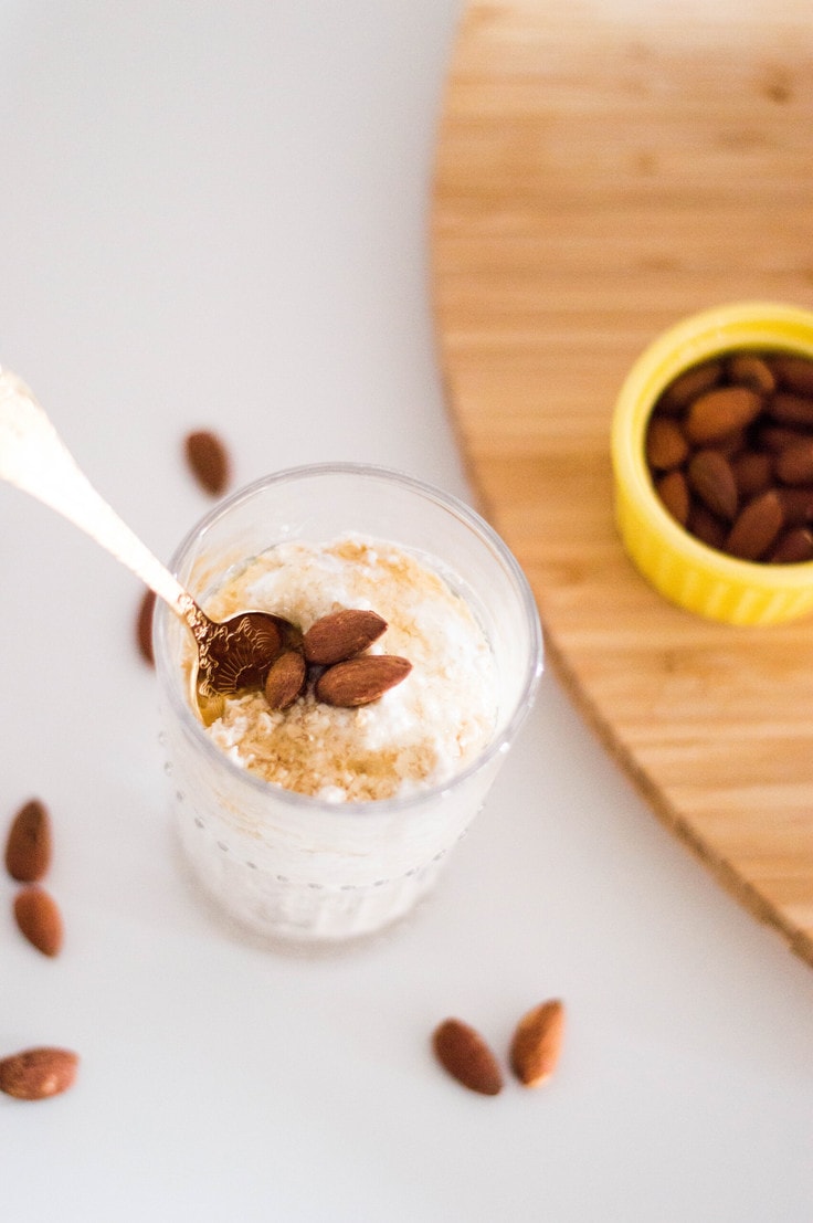 Glass full of overnight oats with almonds on top.
