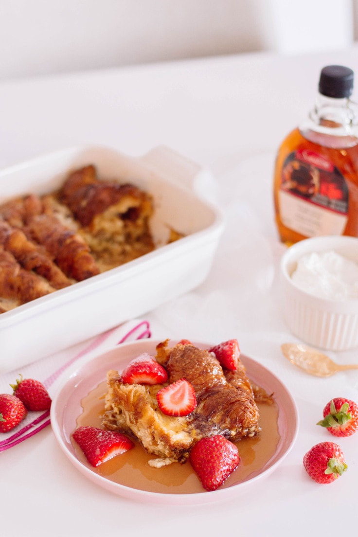 Plate of french toast with strawberries and syrup.