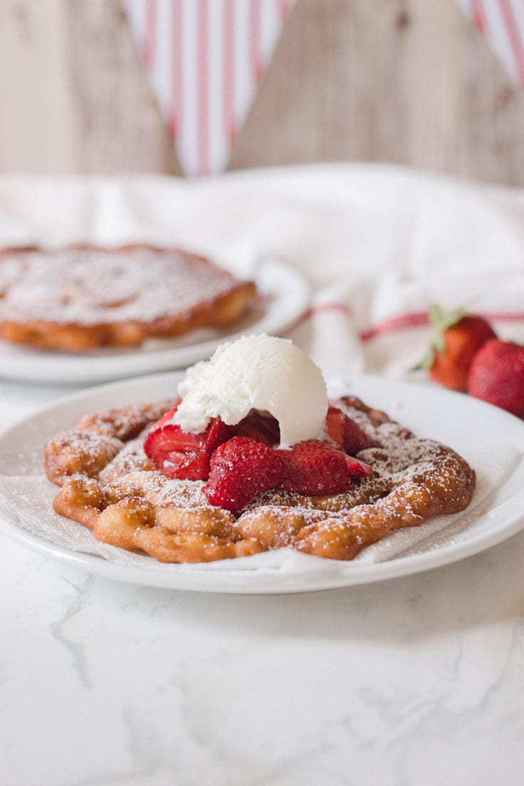 Funnel cake with strawberries and ice cream.
