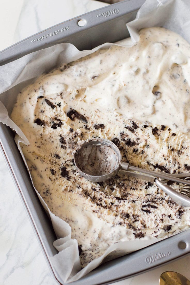 An ice cream scoop in a pan of Oreo ice cream.