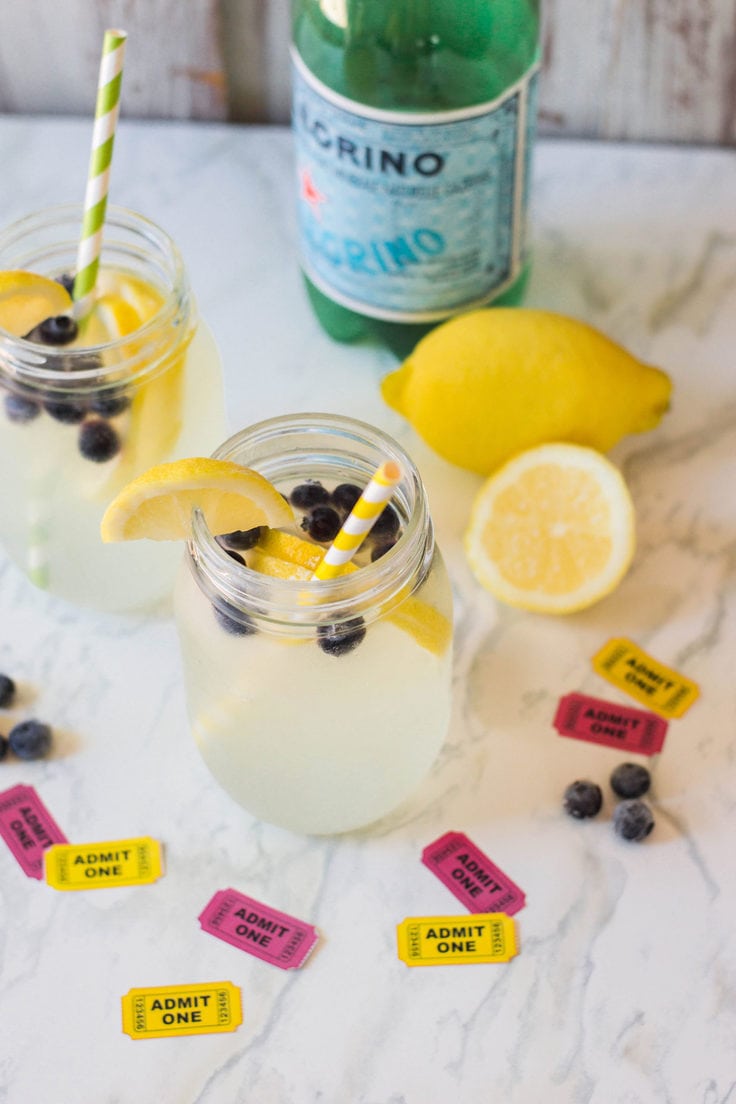 Sparkling lemonade with blueberries beside a bottle of Pellegrino.