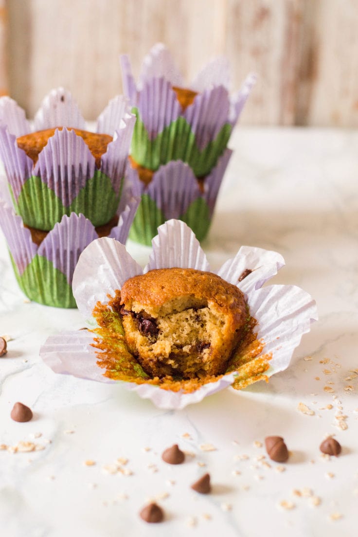 Muffin with a bite out of it and chocolate chips sprinkles around it.