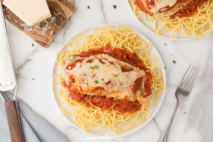 Baked chicken parmesan over pasta.