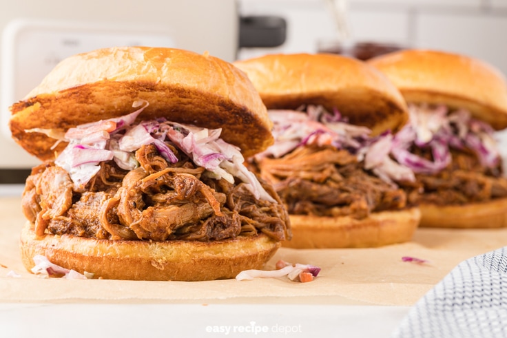 Pulled pork sandwiches on toasted buns with coleslaw topping.