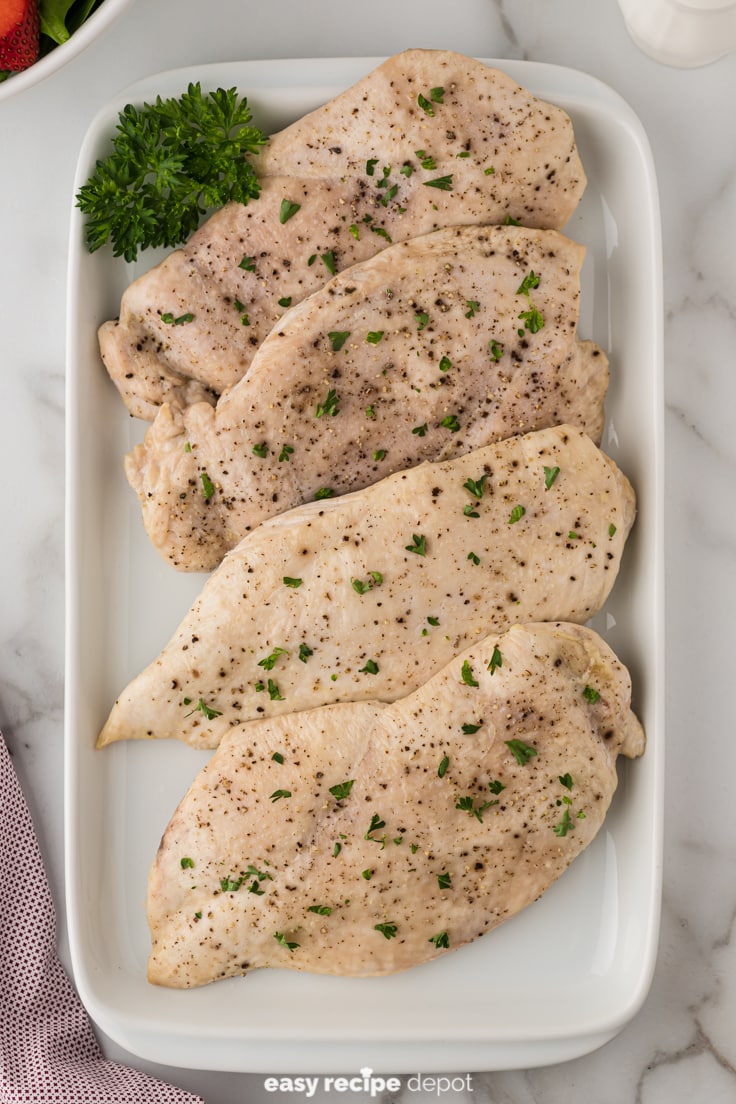 Baked boneless skinless chicken breasts on a serving plate.