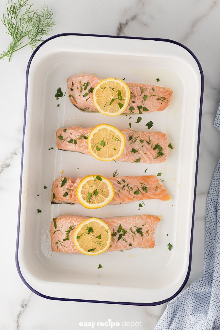 baked salmon from the oven with lemon slices and dill and parsley