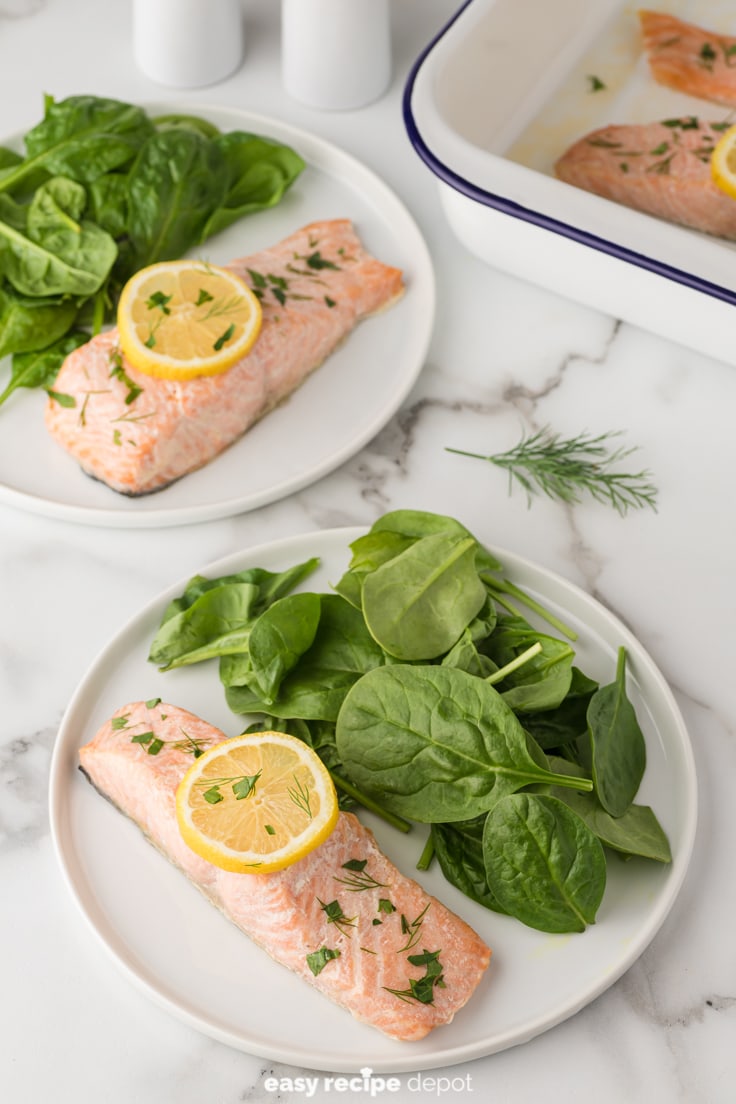 baked salmon with lemon slices and dill and parsley served with a side salad 