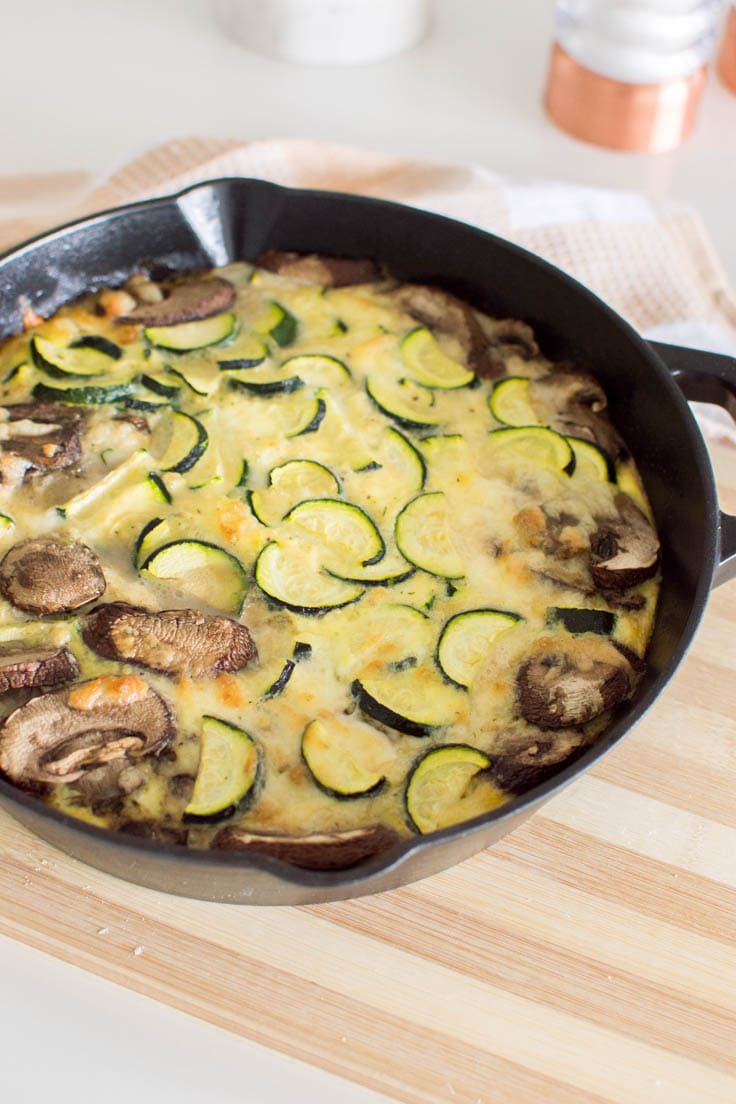 A closeup of a zucchini and mushroom frittata, baked in a cast iron skillet