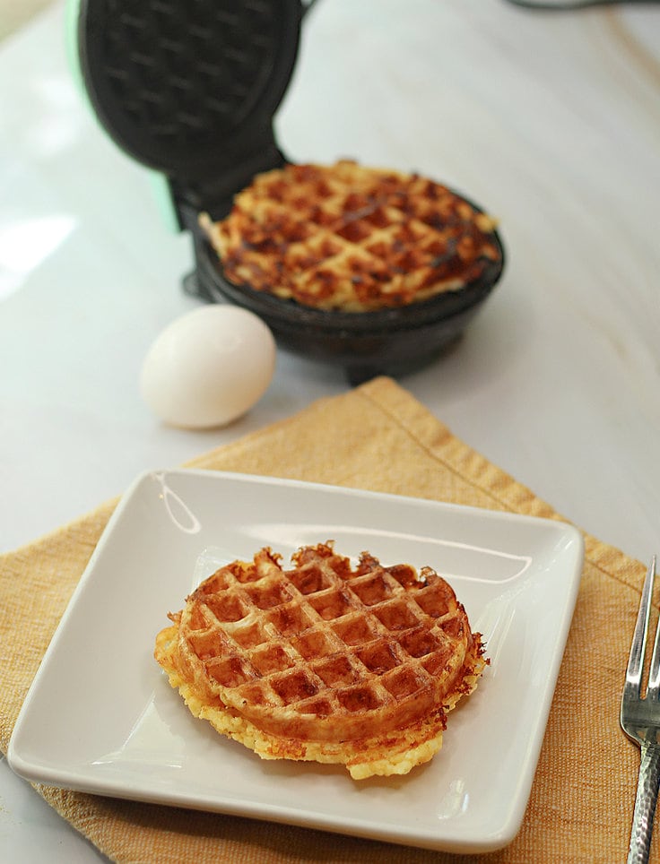 crisp chaffle with waffle iron in the background.