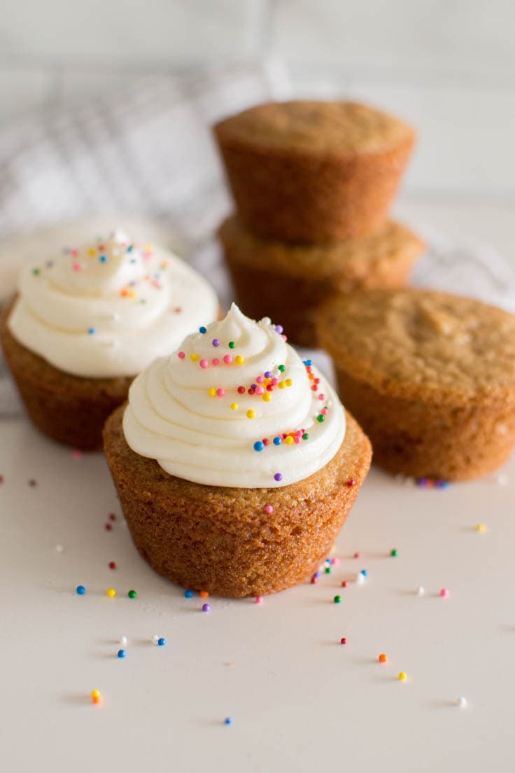 Our recipe for easy frosting, topped with sprinkles, on top of a vanilla cupcake