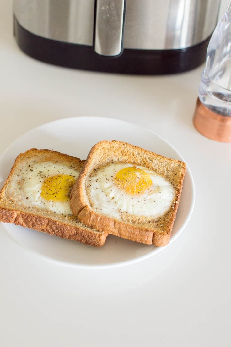 Egg toast on a white plate, sitting on a white background
