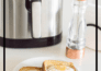 Two slices of air fryer egg toast on a small white plate with an air fryer and a pepper grinder in the background