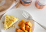 Bird's eye view of maple roasted sweet potatoes on a white plate, next to a piece of frittata and a fork