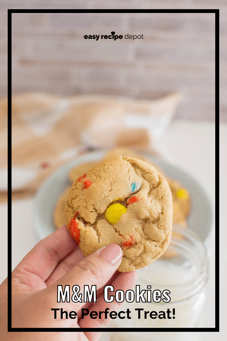 A hand holding up a homemade M&M cookie.