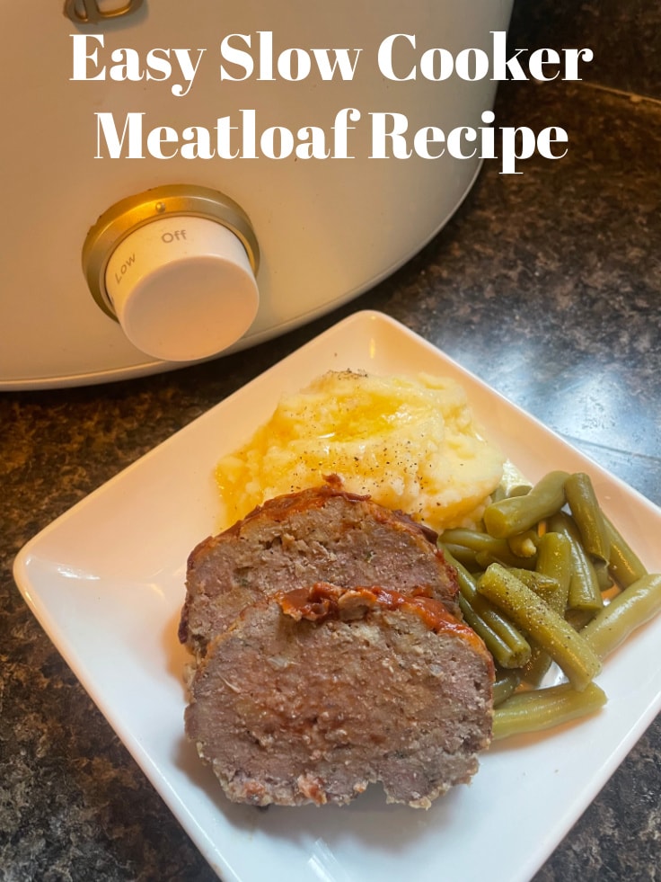 sliced meatloaf on a white plate with vegetables in front of a white slow cooker