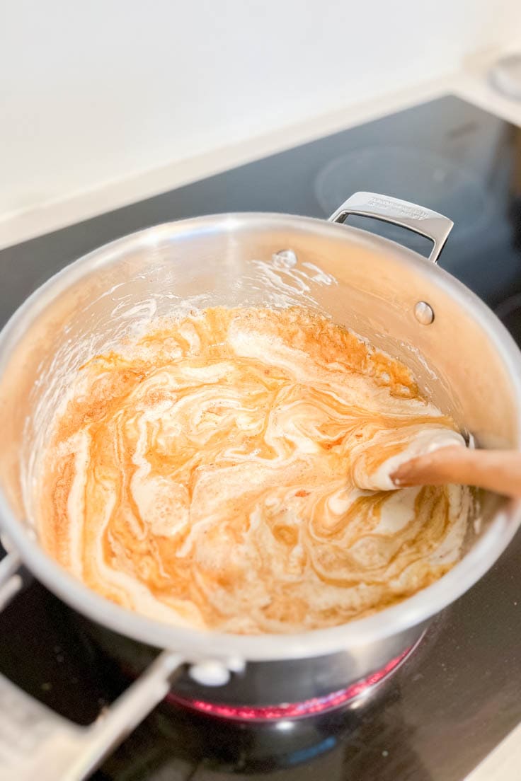 Mixing together melted marshmallows in a large pot with molasses and other spices
