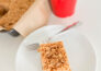 A gingerbread-flavored rice cereal treat on a white plate with a fork sitting next to it