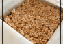 Gingerbread-infused rice cereal treats patted down into a parchment-lined square pan