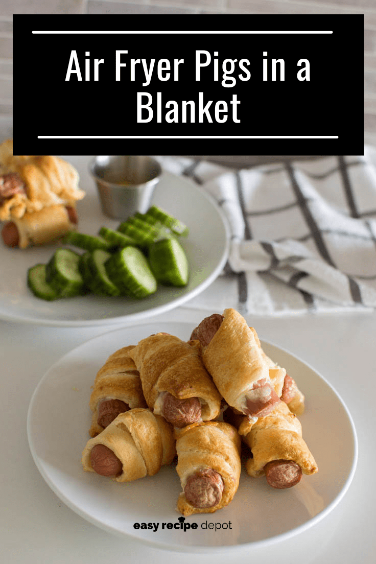A pile of Air Fryer Pigs in a Blanket on a white plate, ready to be eaten, with some more in the background along with dip and slices of cucumber