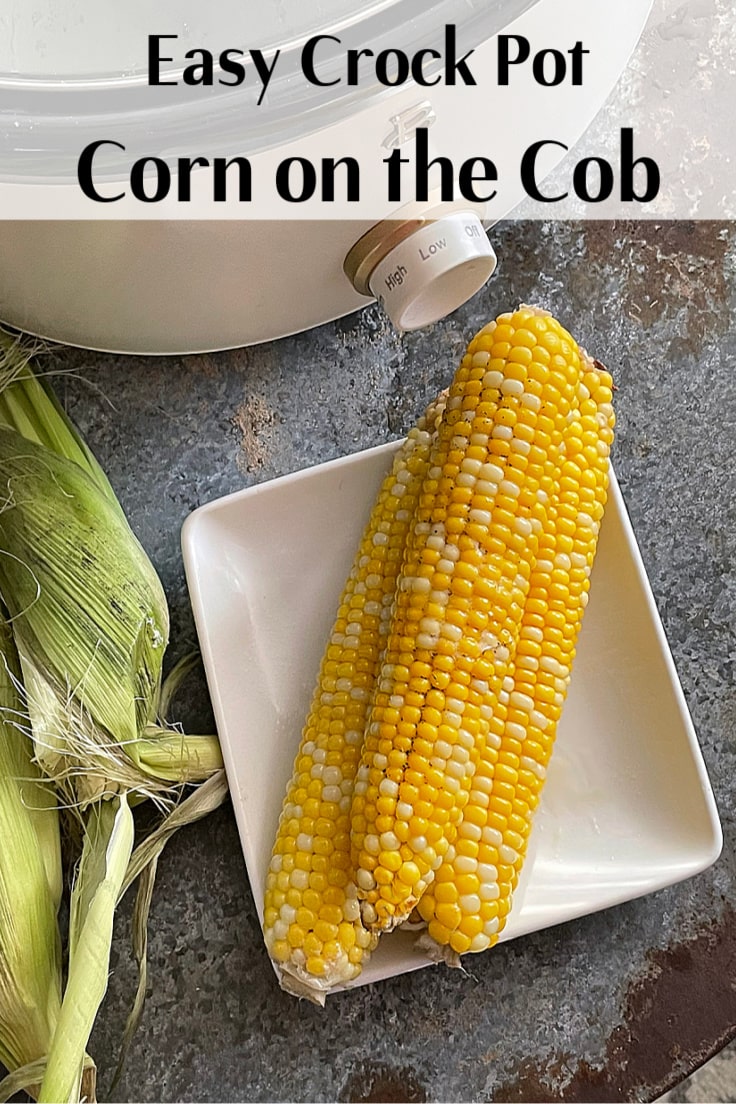 stack of corn on the cob with white plate and white crockpot in the background