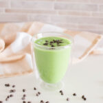Healthy Shamrock Shake surrounded by a tea towel and miniature chocolate chips