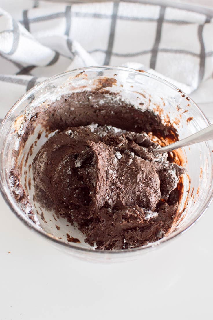Mixing all ingredients to make no bake brownie bites in a large glass bowl