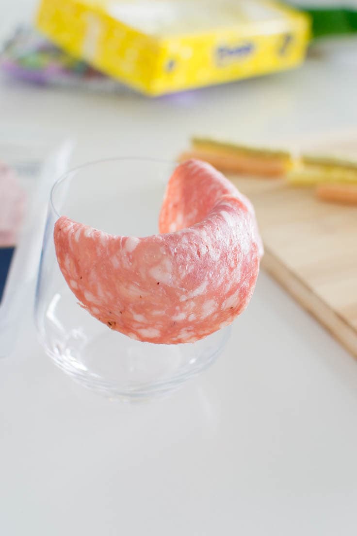 Folding a slice of salami on a drinking glass' rim