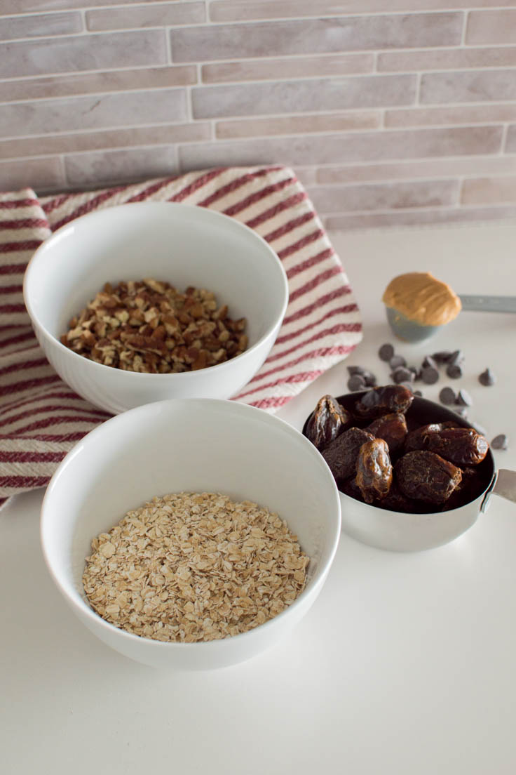Ingredients in white bowls and measuring cups to make Date Energy Balls
