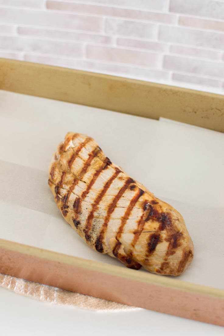 Grilled pork tenderloin in a baking pan ready to be baked in the oven