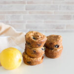 Two stacks of blueberry muffins with a lemon next to the stacks
