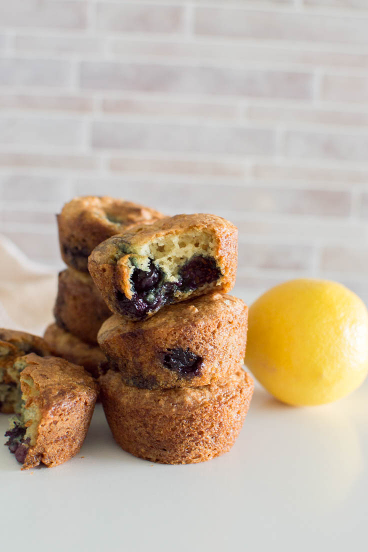 A stack of Lemon Blueberry Muffins and the top one with a bite out of it.
