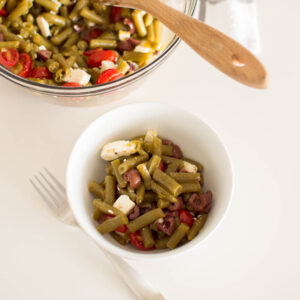 Aerial shot of a green bean salad in a white bowl with a larger serving in the background