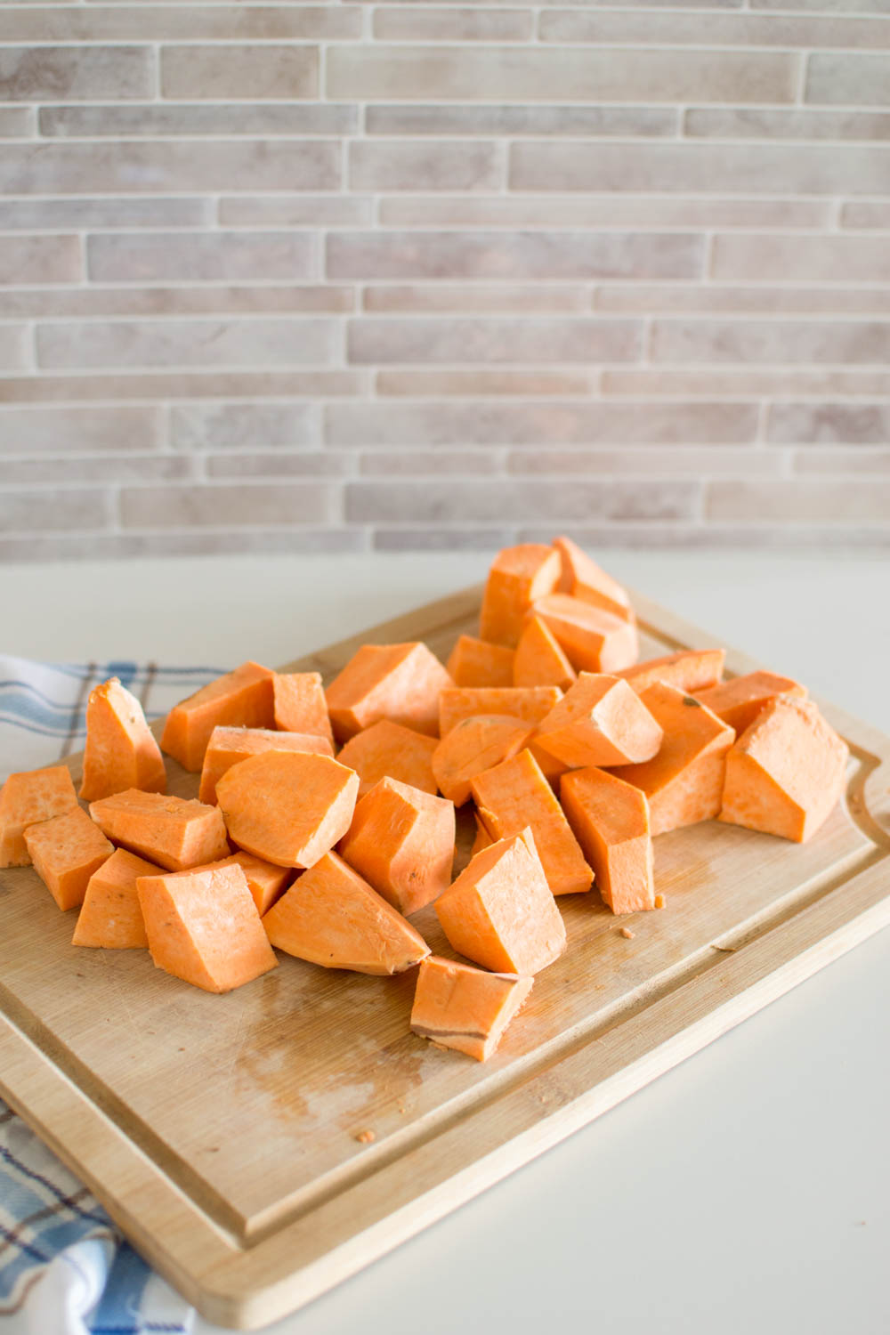 Sweet potatoes cubed on a wooden cutting board
