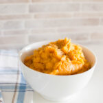 Mashed sweet potatoes with cracked black pepper, served in a white bowl