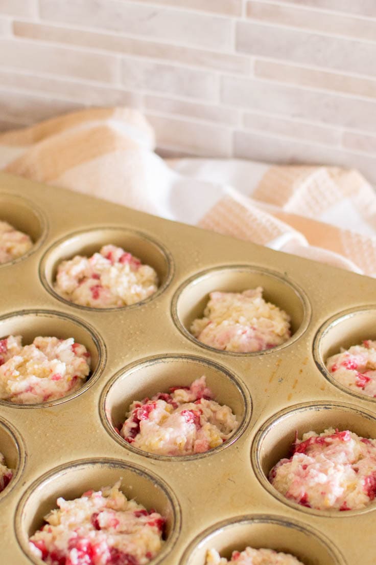 Filling a muffin tin with batter to make Raspberry Streusel Muffins
