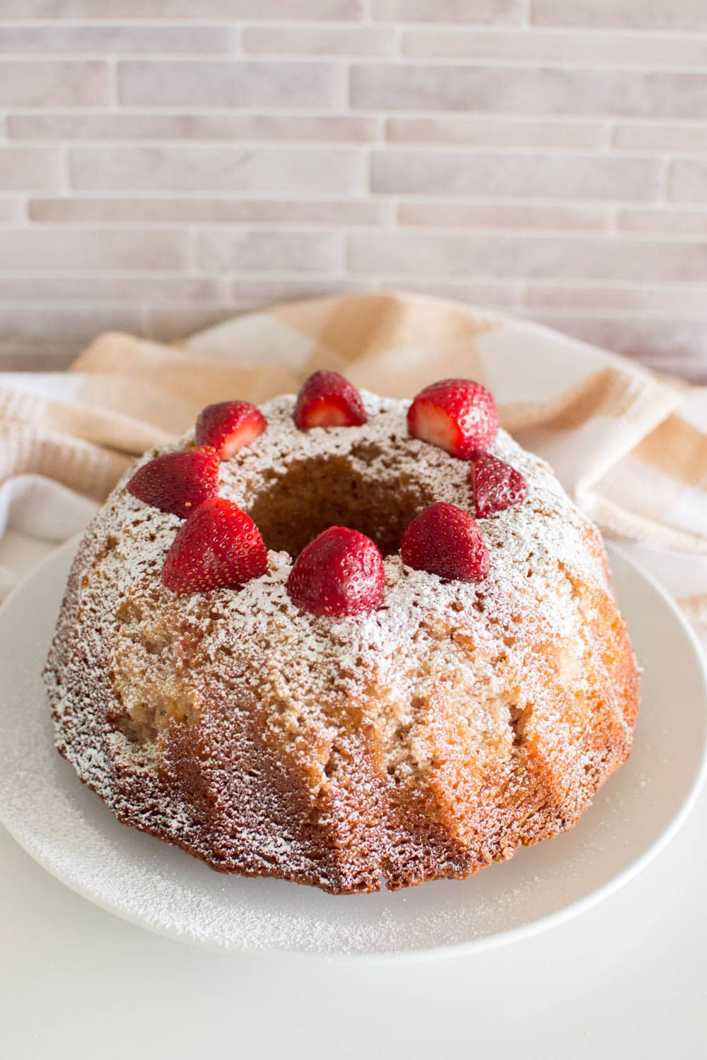 A bundt cake with powdered sugar and strawberries on top