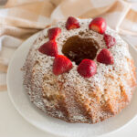 A bundt cake with powdered sugar and strawberries on top
