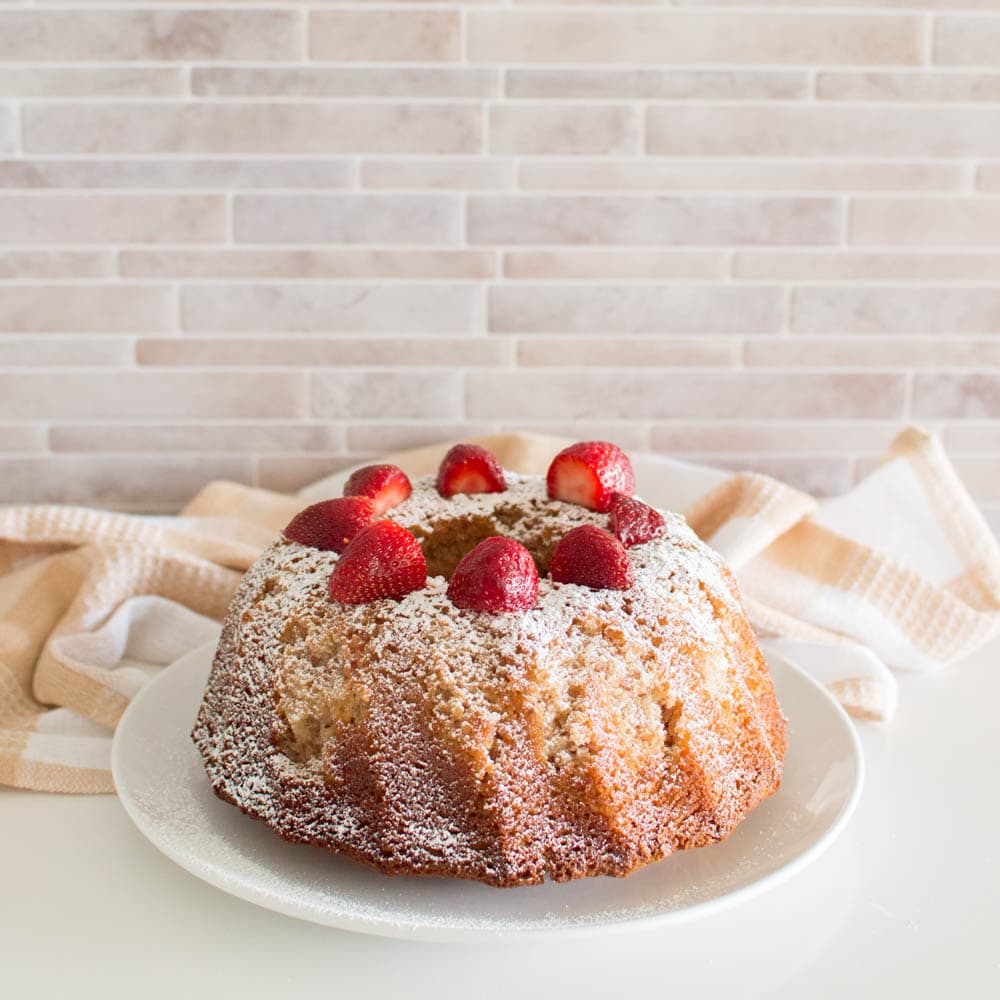 Strawberry bundt cake garnished with fresh strawberries on a white plate