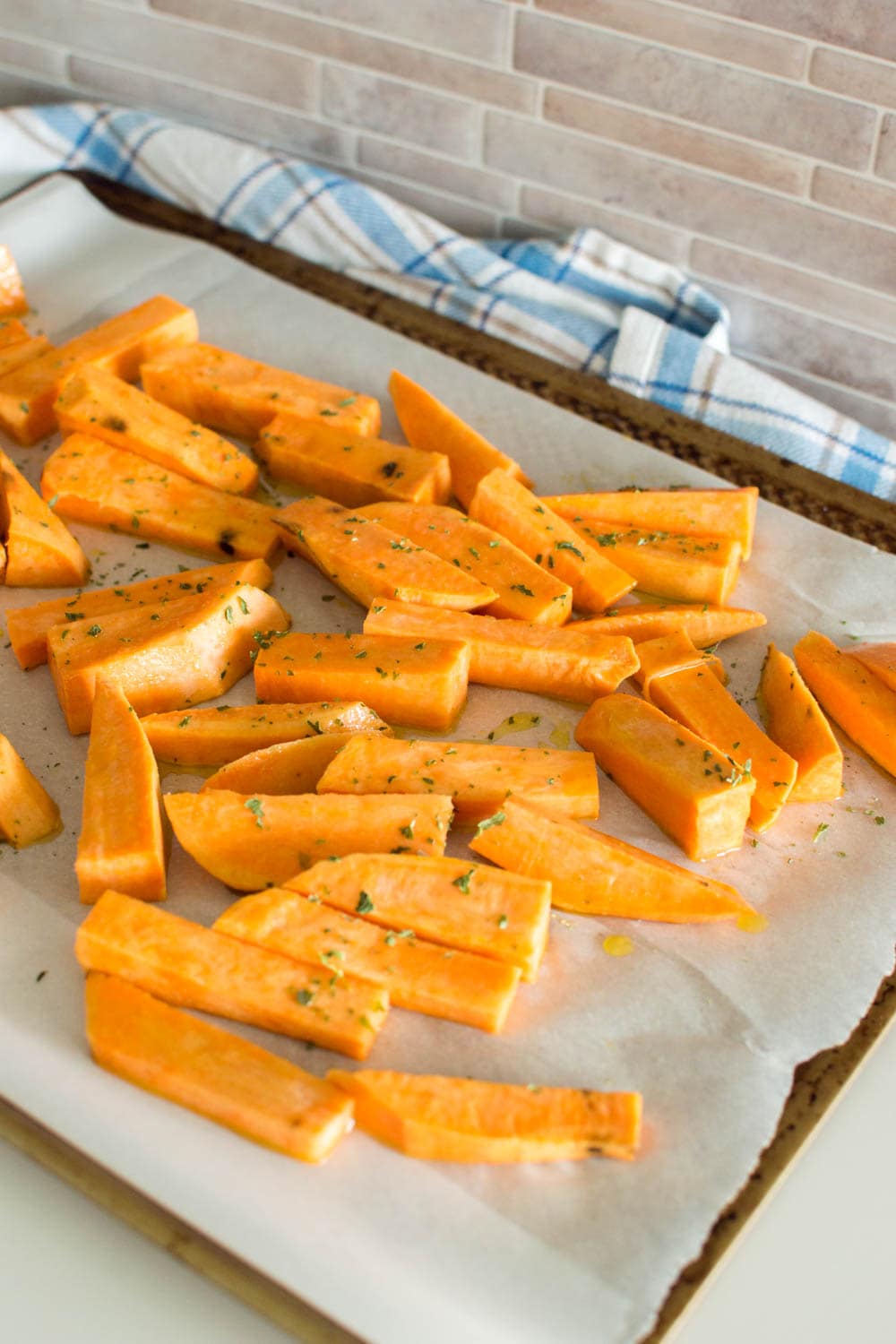Sweet potato fries on a cookie sheet and garnished with dried parsley flakes