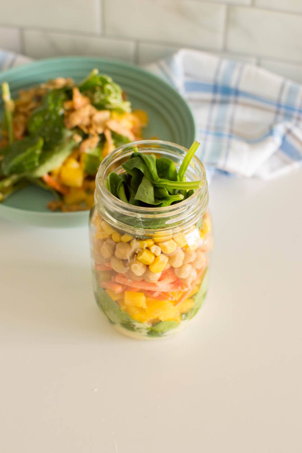 Topping off mason jar salad with spinach