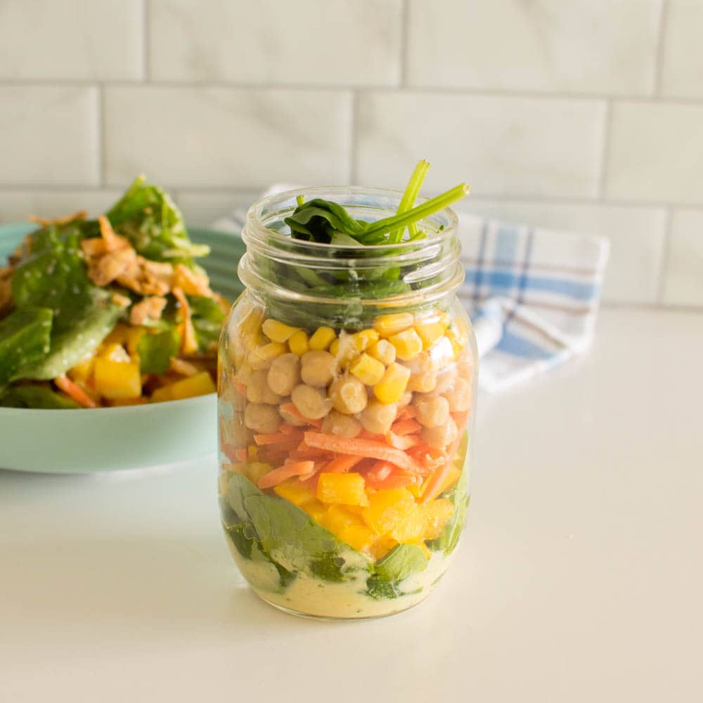 Topping off mason jar salad with spinach