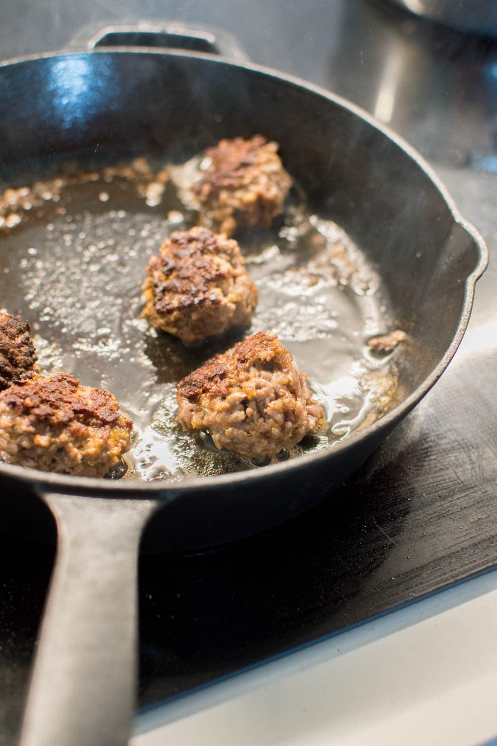 Swedish meatballs cooking in a cast-iron skillet