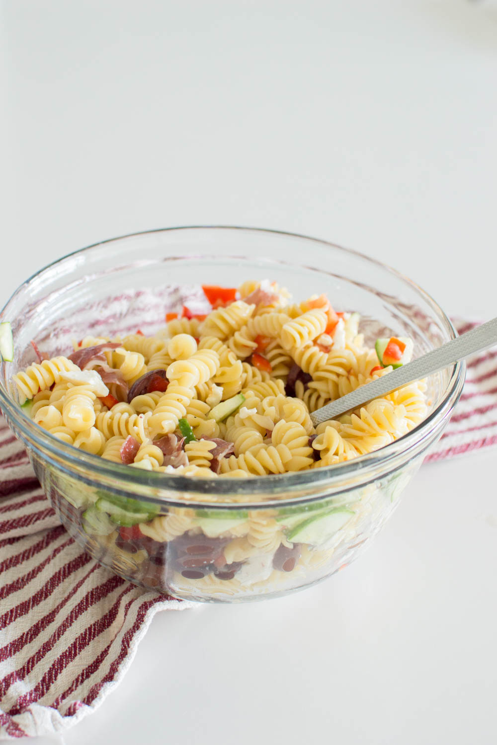 A large glass bowl filled with homemade pasta salad