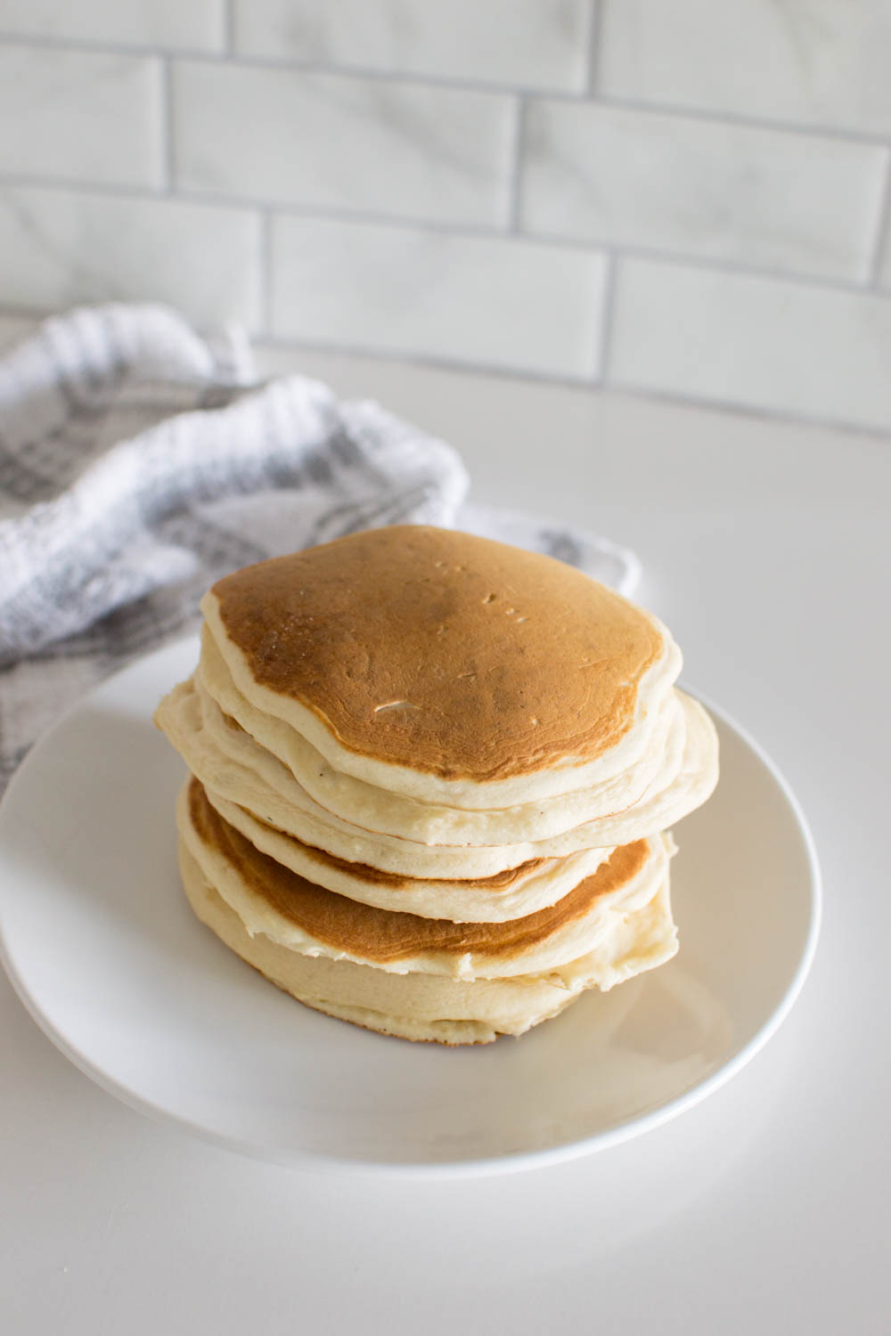 A stack of homemade pancakes on a white plate