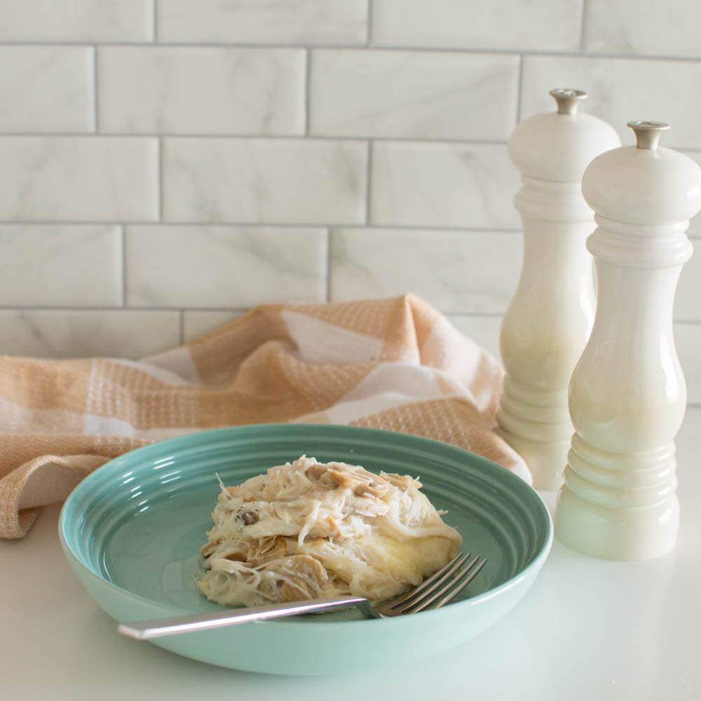 A generous portion of tetrazzini served on a green plate, surrounded by a plaid tea towel and salt and pepper shakers