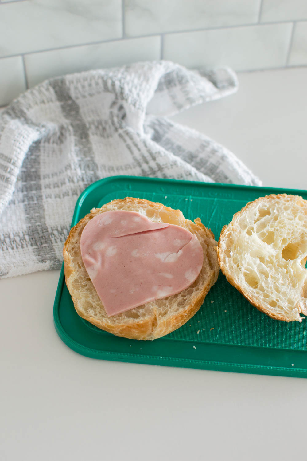 Add luncheon meat on a croissant half to start making a cookie cutter slider