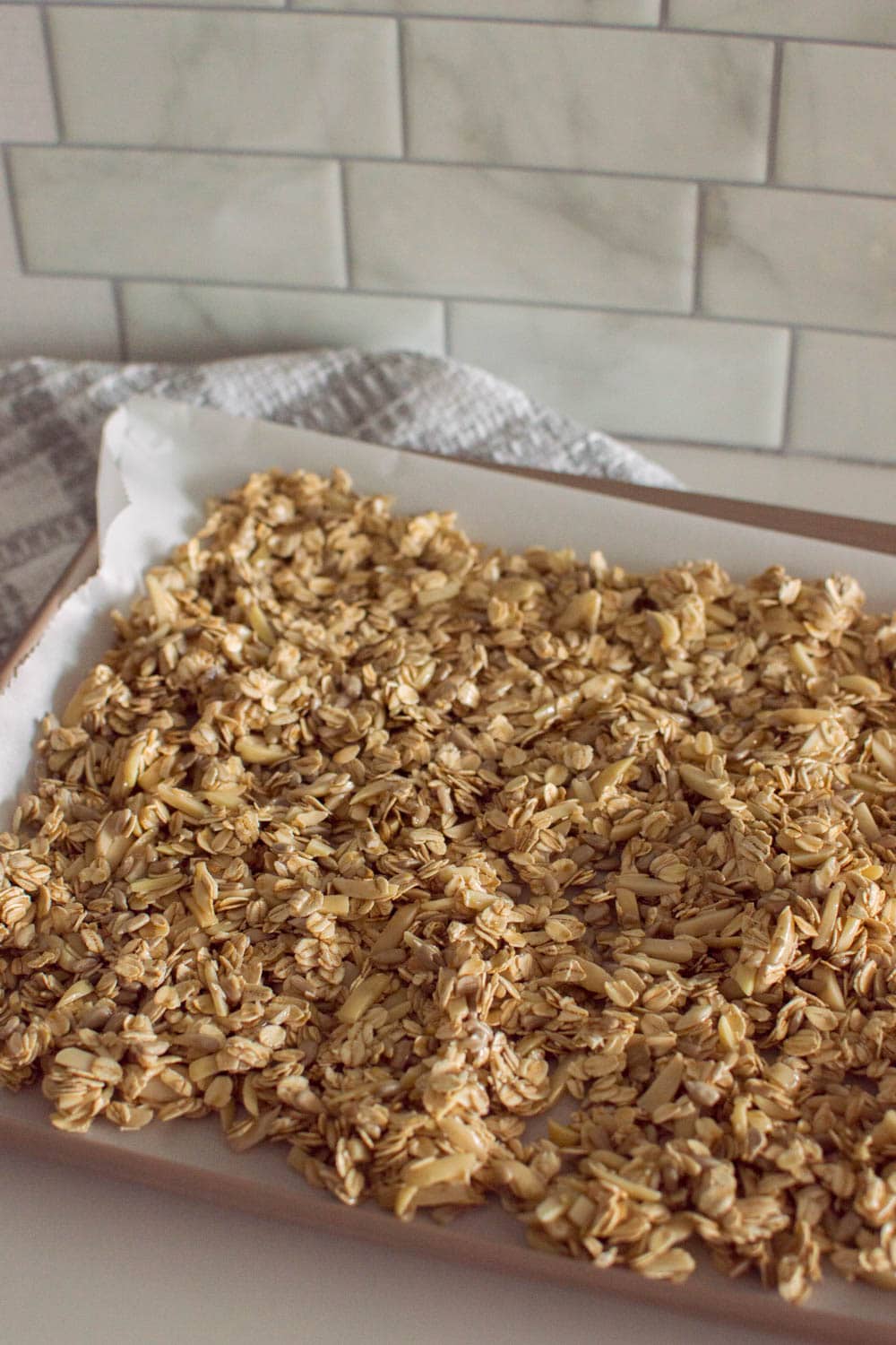 Laying out granola mixture on a cookie sheet, ready for baking