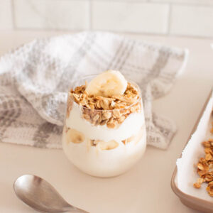 Our easy homemade granola recipe served in a glass with yogurt and banana