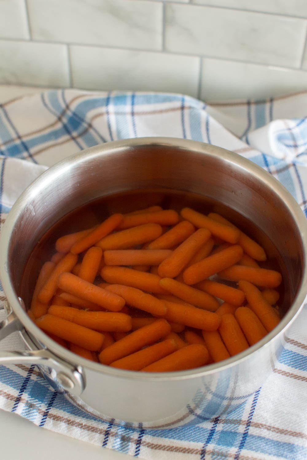 Adding baby carrots into a pot of boiling water